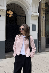a lady in a white top, a pink tweed jacket and a pair of black pants